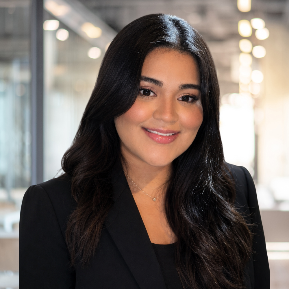 Smiling professional woman in a business suit at a modern office setting.