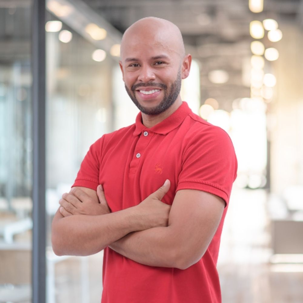 Businessman in a blue blazer standing confidently in an office environment.