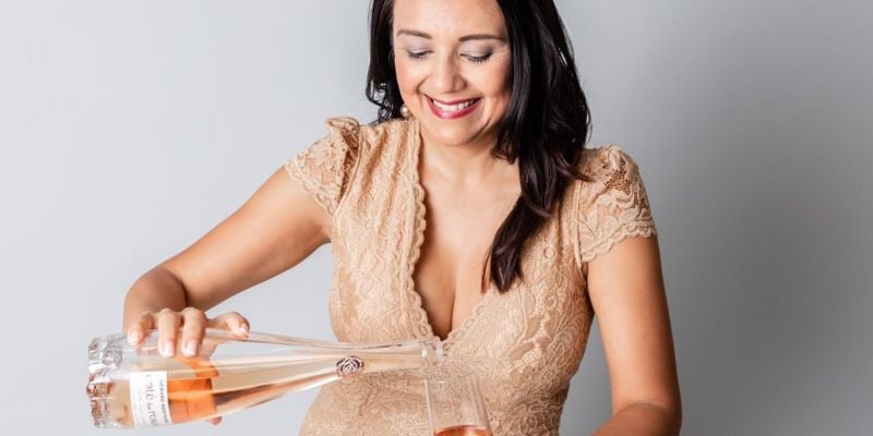 Woman in gold lace dress pouring rosé wine